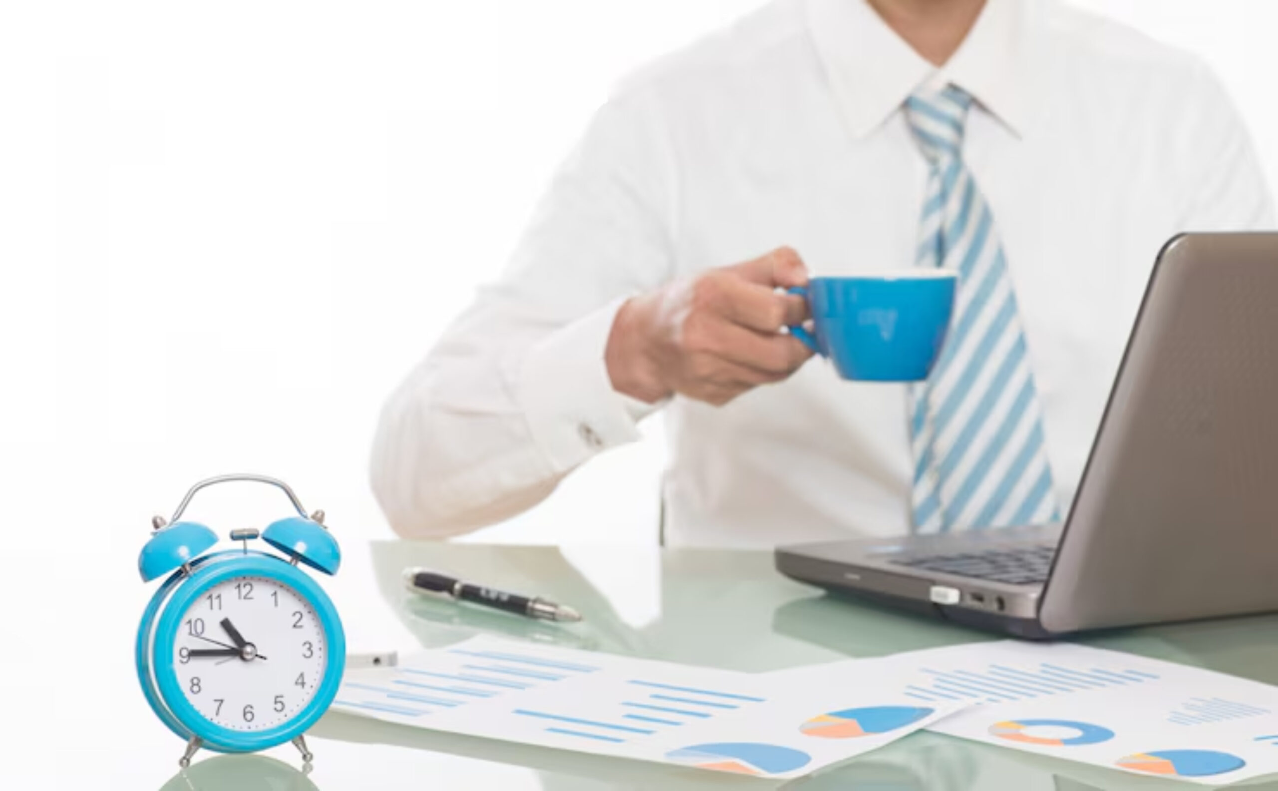 A man in a white shirt and blue tie holds a blue coffee cup near a laptop, a blue alarm clock, and graphs on his desk.