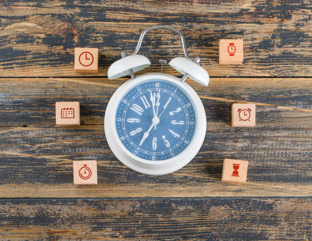A white alarm clock shows 10:10, surrounded by six wooden blocks with time-related icons, on a rustic wooden surface. The scene conveys themes of time management.